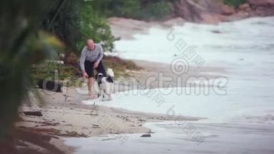 快乐的年轻英俊的男人在暴风雨的天气里玩狗和粘在热带海滩上。 <strong>1920</strong>x1080